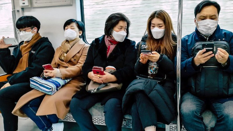illustration: several commuters are seen wearing masks on board a train.